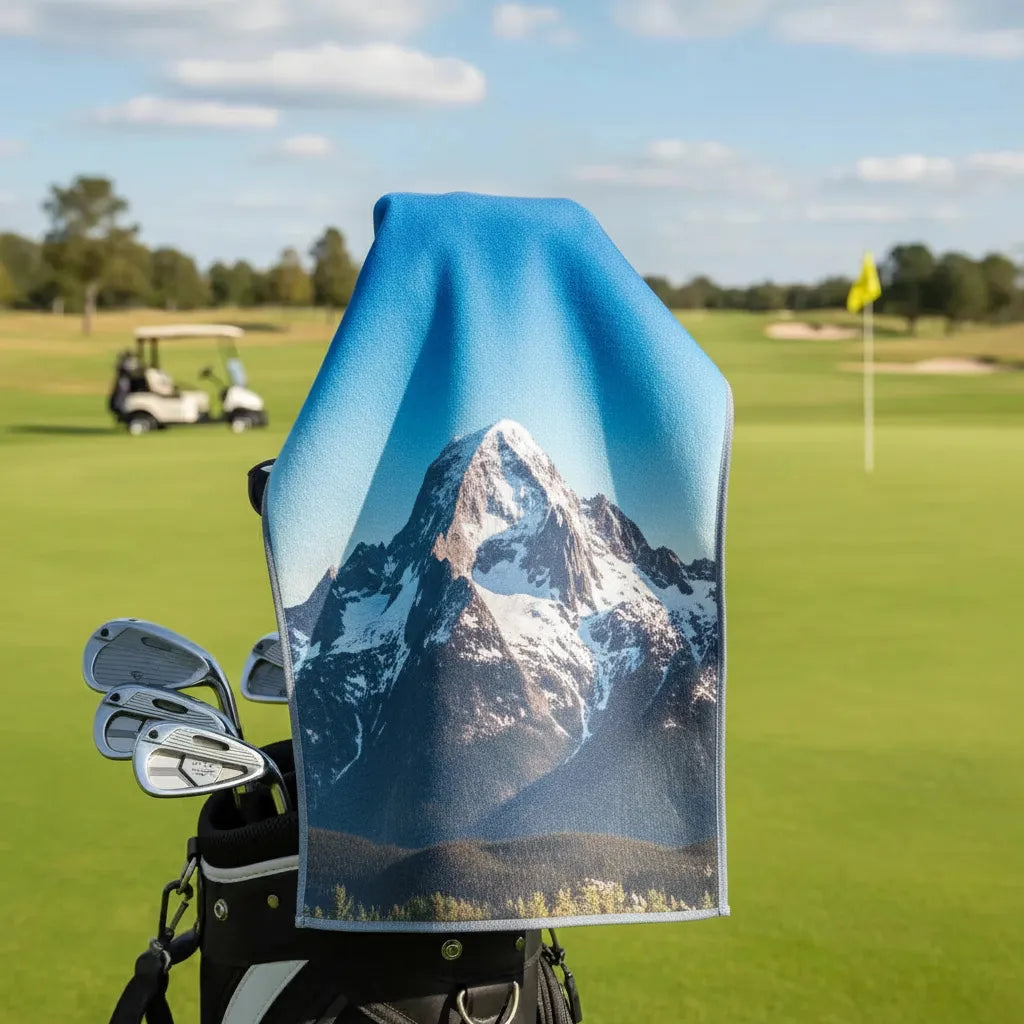Golf towel with mountain design on a golf bag in a golf course setting